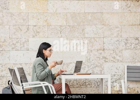 Minimal side view portrait of young businesswoman in online meeting at outdoor cafe Stock Photo