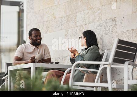 Portrait of two young people enjoying coffee in outdoor cafe, copy space Stock Photo