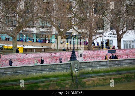 People are seen queuing towards a vaccination centre at St Thomas’ Hospital behind red hearts painted on the National Covid Memorial Wall