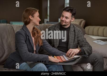 Joyous woman and man examining fabric samples by touch Stock Photo