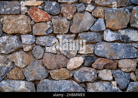 Background texture of masonry wall made of natural multicolored stones. Stock Photo