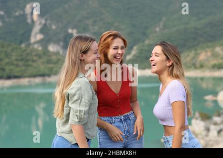 Three happy fiends laughing and talking in a lake on summer vacation