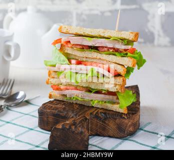 Sandwich for breakfast with stuffed tomatoes with ham and lettuce on a light wooden background. Selective focus. Stock Photo
