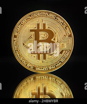 Single gold bitcoin coin with reflection. Isolated on black background Stock Photo