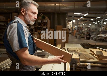 Focused photo on carpenter holding wooden bar Stock Photo