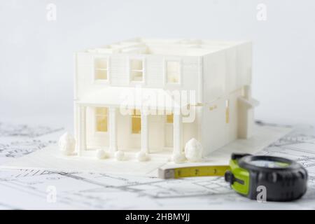 3D model of the family house without roof printed on a 3D printer and measuring tape in foreground Stock Photo