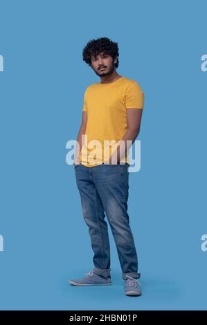 Sad serious dark-haired man posing against the blue background Stock Photo