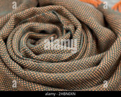 The interwoven of green and orange threads of the handmade fabric. Draped woolen shawl or plaidy, close up Stock Photo