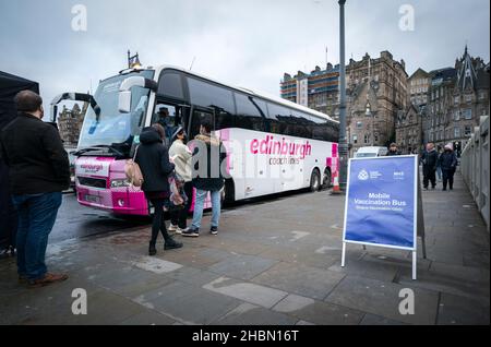 People queue along Waverley Bridge in Edinburgh, for the mobile vaccination bus as the coronavirus booster vaccination programme is ramped up to an unprecedented pace of delivery, with every eligible adult in Scotland being offered a top-up injection by the end of December. Picture date: Monday December 20, 2021. Stock Photo