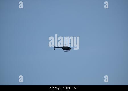 Side view of a helicopter hovering over a clear blue sky. Stock Photo