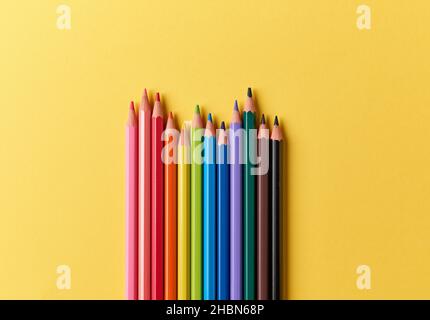 wooden color pencils on yellow paper background, top view Stock Photo