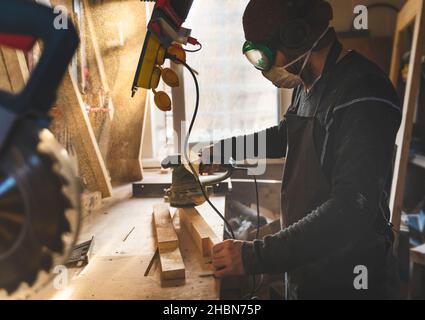 Man working with wood in workshop using sanding machine. Stock Photo