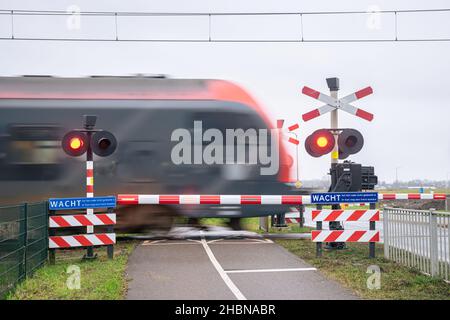 A train passes a railway crossing at high speed. Train is blurred by the speed of the train Stock Photo