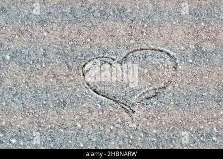 Heart drawn by the hand of a man on a marble wall in a blue close-up.  Icy stone wall with scratched heart Stock Photo