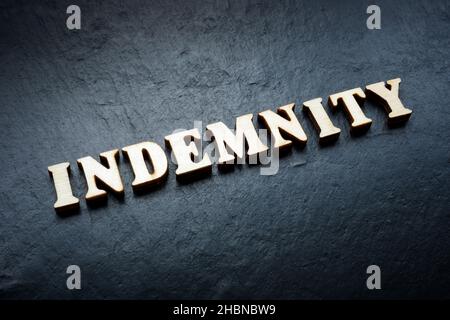 Word indemnity from wooden letters on the rock. Stock Photo