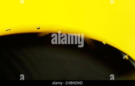Cola drink with few bubbles in glass, yellow background - abstract detail Stock Photo