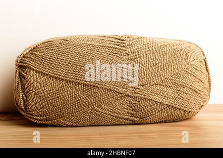 One light brown knitting wool threads for sewing or from embroidery isolated on a raw wooden table, side view of textile materials Stock Photo