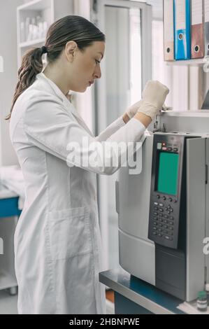 Portrait of female researcher doing research in a chemistry lab. Gas chromatograph analyzer Stock Photo