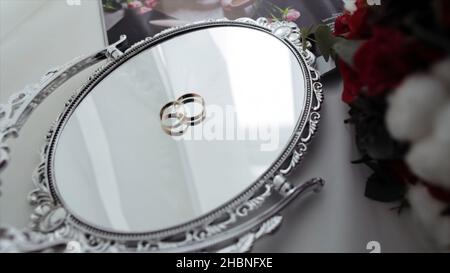 Beautiful wedding rings on a vintage mirror. wedding rings on the mirror surface. Stock Photo