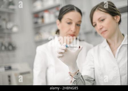 Two scientists holding a test tube with sample in the medical or scientific laboratory Stock Photo