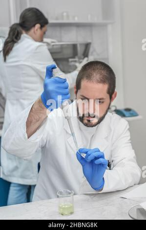 Two scientists in the laboratory filling test tubes with pipette. Close ...