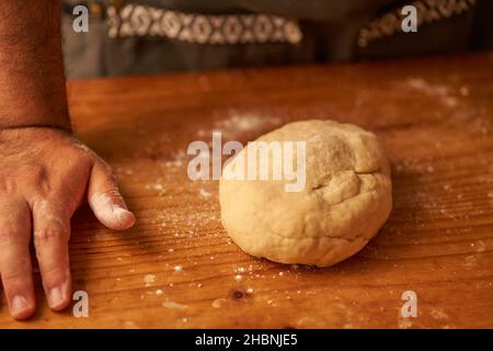 cook's hand rests on the counter next to his freshly prepared dough. Stock Photo