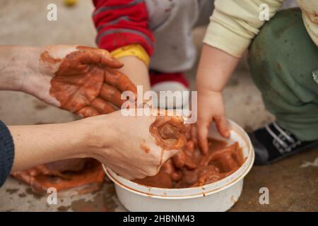 Woman squeezes the clay before molding figures together with children Stock Photo