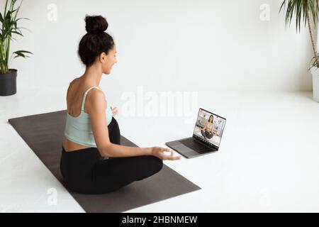 Online Yoga. Woman Having Video Conference With Instructor While Training At Home Stock Photo