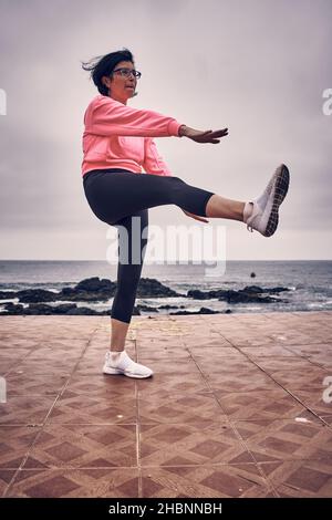 Young woman performs stretching and balancing exercises in front of the sea. sport Stock Photo