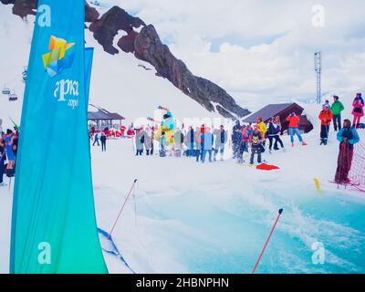 Russia, Sochi 11.05.2019. A snowboarder in a cap with his back to front and bright clothes jumps beautifully on the springboard and all people are wat Stock Photo
