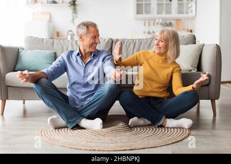 Mature Couple Doing Yoga Sitting In Lotus Position At Home Stock Photo