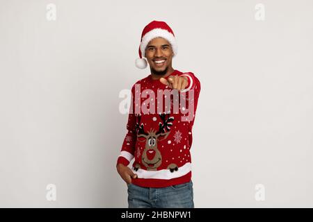Charismatic handsome black guy in Santa hat pointing at camera Stock Photo