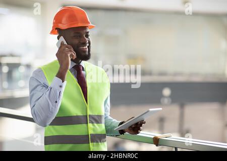 African american architect having phone conversation, using pad Stock Photo