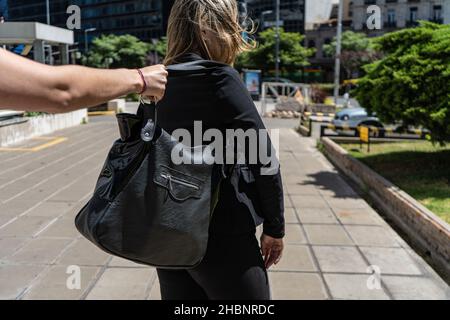 A Thief wanting to steal a purse from a woman's shoulder. Stock Photo