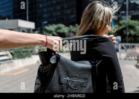 A Thief wanting to steal a purse from a woman's shoulder. Stock Photo