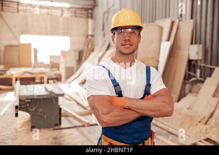 Joyful male worker standing in carpentry workshop Stock Photo