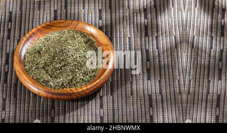 Dried organic tarragon leaves in wooden bowl - Artemisia dracunculus Stock Photo