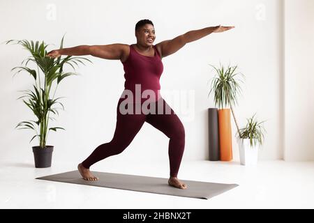 Motivated black woman in sportswear doing exercises, full length shot Stock Photo