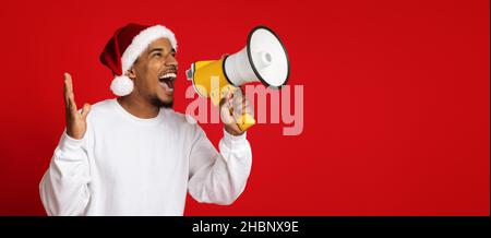 Emotional african american man in Santa hat using megaphone Stock Photo