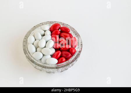 Traditional Turkish Hard Almond red and white candies in crystal candy bowl on white with copy space. Stock Photo