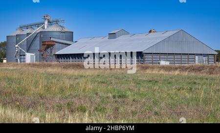 A bank of silos and a large storage shed near a railway line in NSW Stock Photo