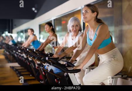 Young girl on training using bike in gym Stock Photo