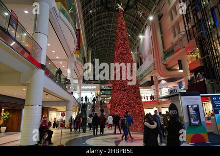 Toronto's Eaton Center is a multi-level indoor mall, with bright Christmas decorations and shoppers wearing face masks due to the pandemic Stock Photo