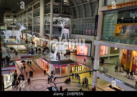 Toronto's Eaton Center is a multi-level indoor mall, with bright Christmas decorations and shoppers wearing face masks due to the pandemic Stock Photo