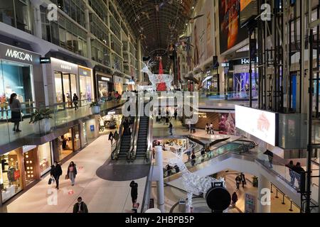 Toronto's Eaton Center is a multi-level indoor mall, with bright Christmas decorations and shoppers wearing face masks due to the pandemic Stock Photo