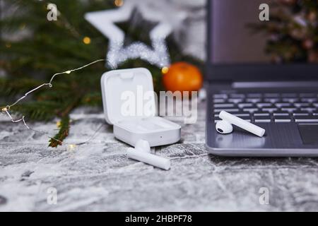 Wireless earphones and laptop near Christmas decorations. Freelance, remote work, taking webinar, calling to family concept. Christmas, New Year's pre Stock Photo