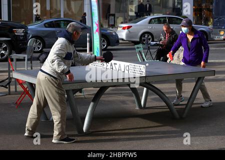Two people of Asian ethnicity play ping pong on a Cornilleau Park Outdoor table in Plaza 33 public space near Herald Square in New York City Stock Photo