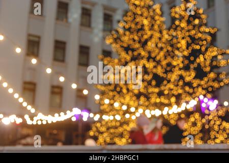 Christmas trees in christmas light garland on background of multi storey building. Blurred image. Wallpaper Stock Photo