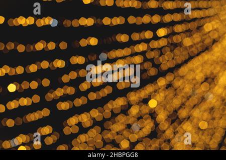 Christmas light garland on dark background. Blurred image. Wallpaper. Stock Photo