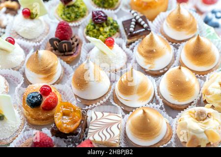 Assorted different mini cakes with cream, chocolate and berries- Sweets offered at the pastry shop. Stock Photo